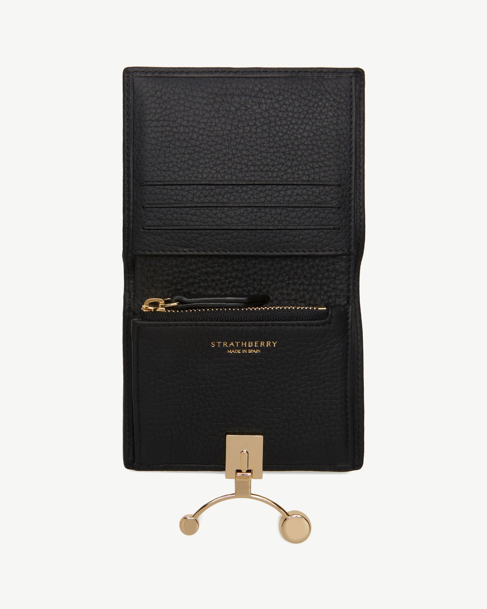 Black leather designer wallet with gold clasp on a neutral editorial background