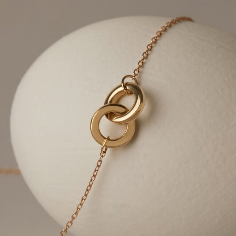Layered thin solid gold chain necklaces flat lay on neutral background