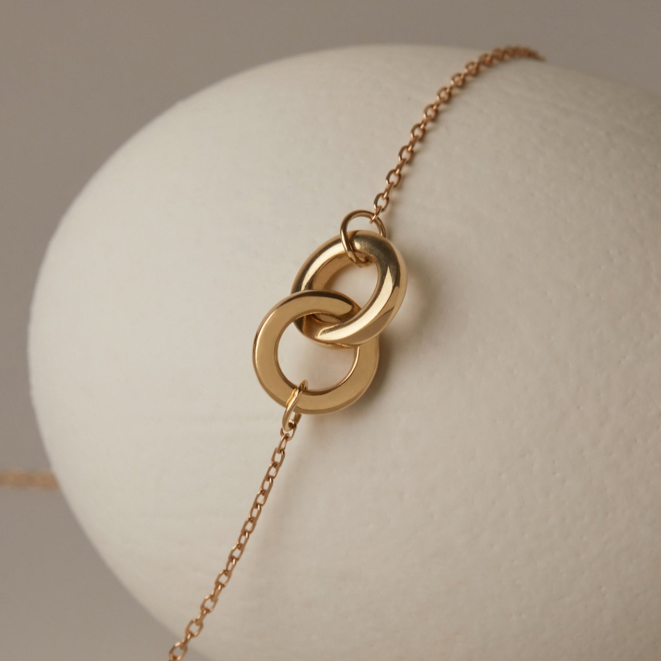 Layered thin solid gold chain necklaces flat lay on neutral background